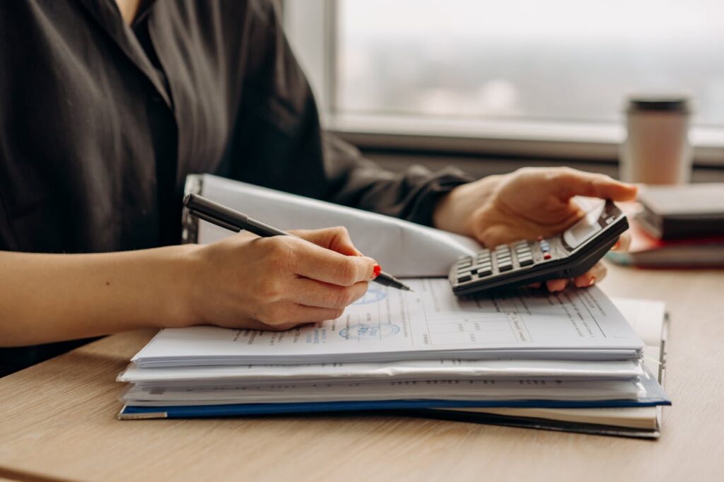 Accountant using a calculator and reviewing financial paperwork for bookkeeping and business reporting