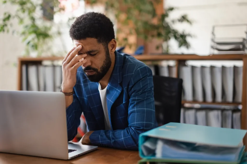 Stressed business owner working on laptop while dealing with cash flow problems and financial pressure.